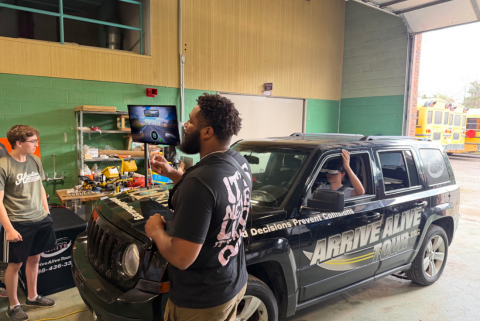 man talking to students in front of a car